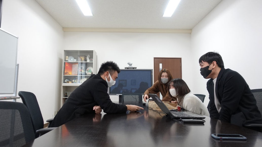 【写真】浅賀さんから写真を見せてもらう学生広報スタッフ